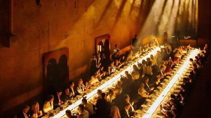 Grand banquet de plusieurs dizaines de convives traversé de faisceaux de lumière