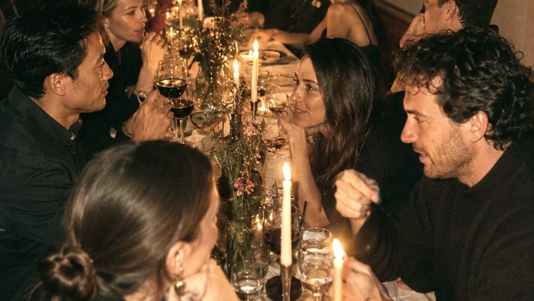 Convives en grande conversation autour d’une table éclairée aux bougies