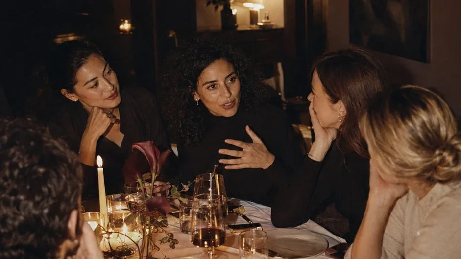 Quatre femmes en conversation sérieuse autour d’une table aux chandelles