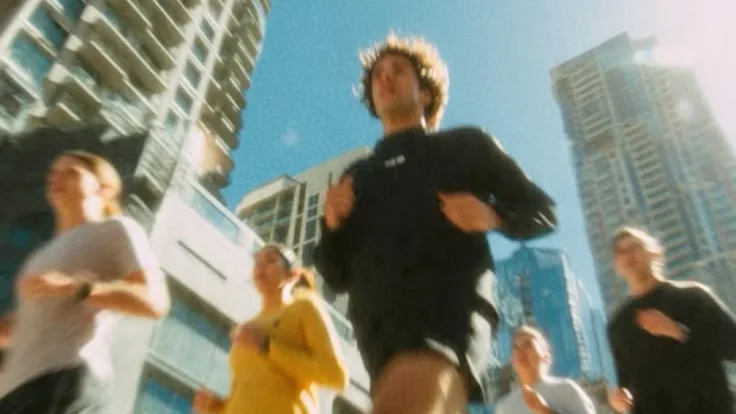 Groupe de coureurs dans une rue bordée de tours, photographié en contre-plongée