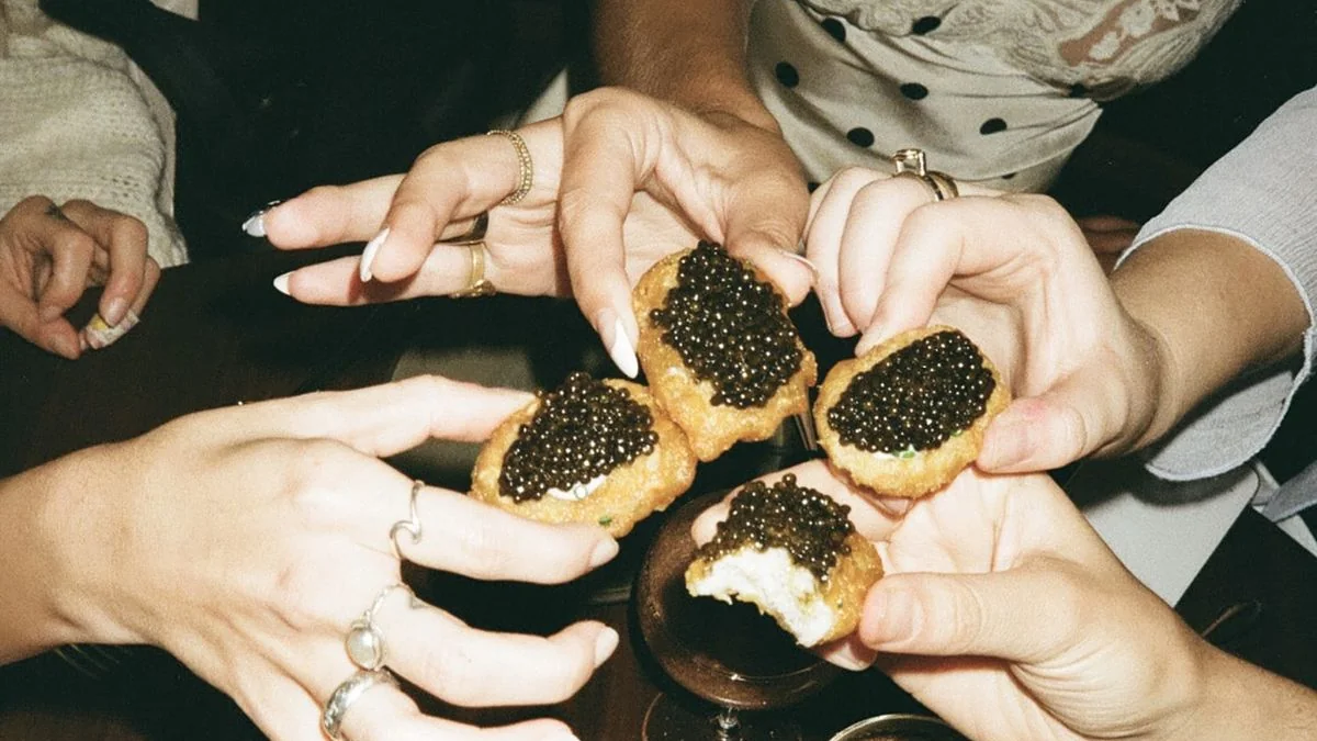 Mains qui partagent des blinis au caviar autour d’une table