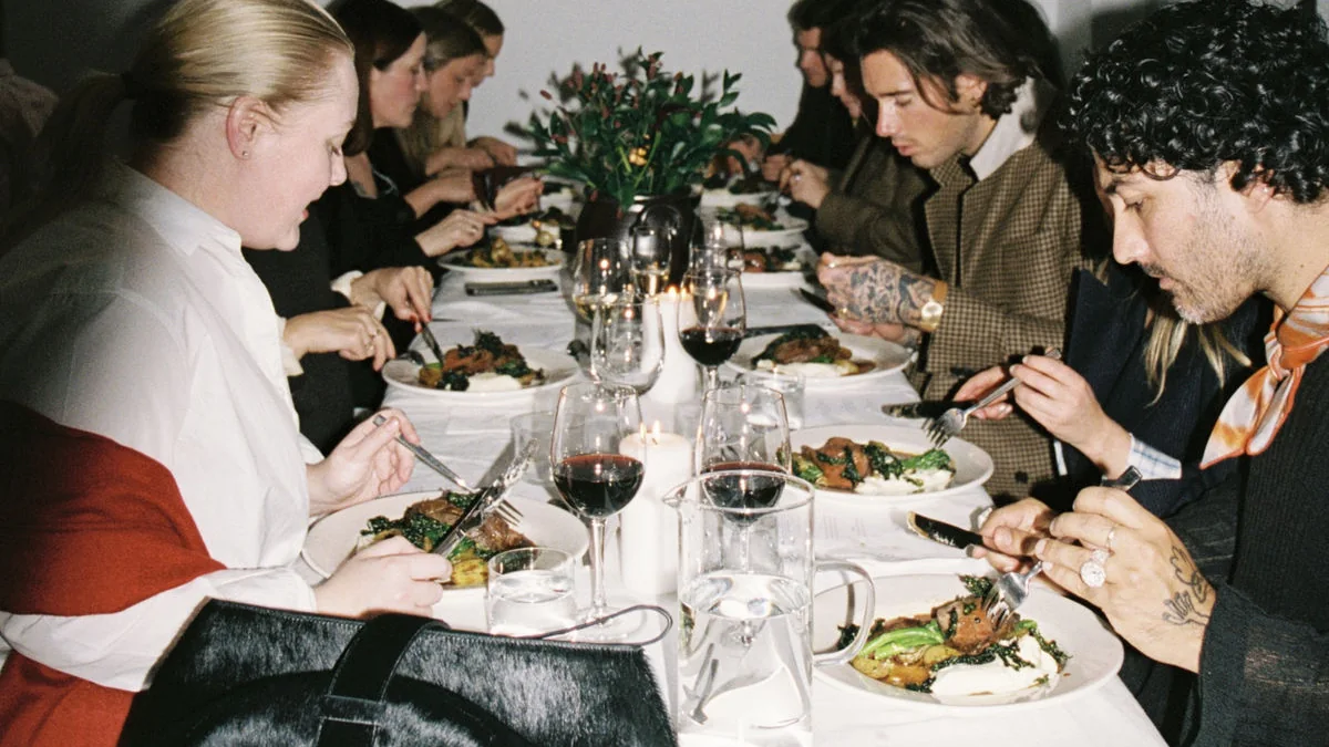Longue table nappée de blanc où les convives mangent en silence, photo argentique